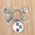 Keychain with paw print charm and measurement details on a dark surface