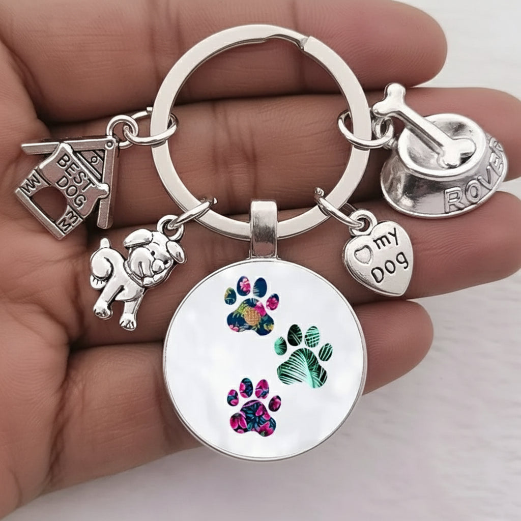 Silver keychain with colorful paw prints and various charms held in a hand.